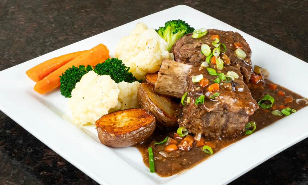 Slow-braised Guinness short ribs with roast potatoes and vegetables, a signature restaurant dinner entrée