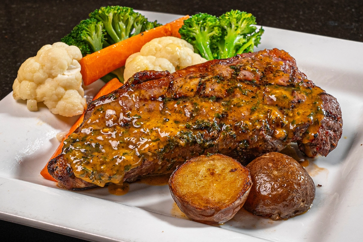 Grilled New York steak with herb butter, roast potatoes and vegetables for a hearty dinner at Symposium Cafe