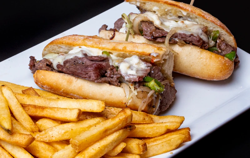 Philly cheese steak sandwich with shaved prime rib, Swiss cheese, peppers and onions, a lunch entree at Symposium Cafe