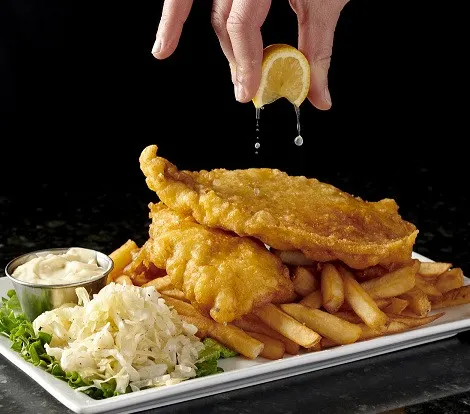 Oshawa dinner spot serving golden fish and chips with fries, creamy coleslaw, tartar sauce and lemon.