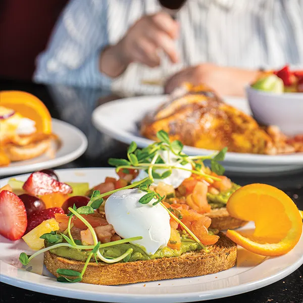 Avocado toast with poached eggs and fresh fruit at Symposium Cafe Oakville