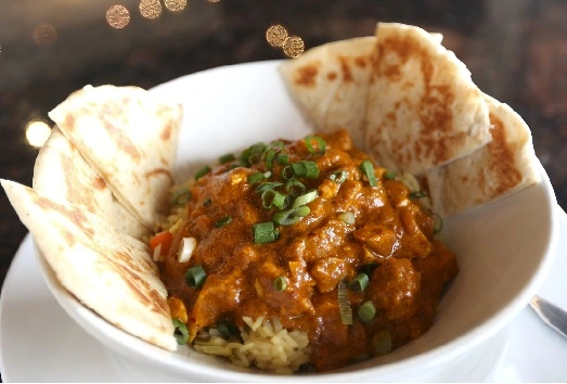 Butter Chicken Rice Bowl entree with pita bread from Symposium Restaurant Ajax menu