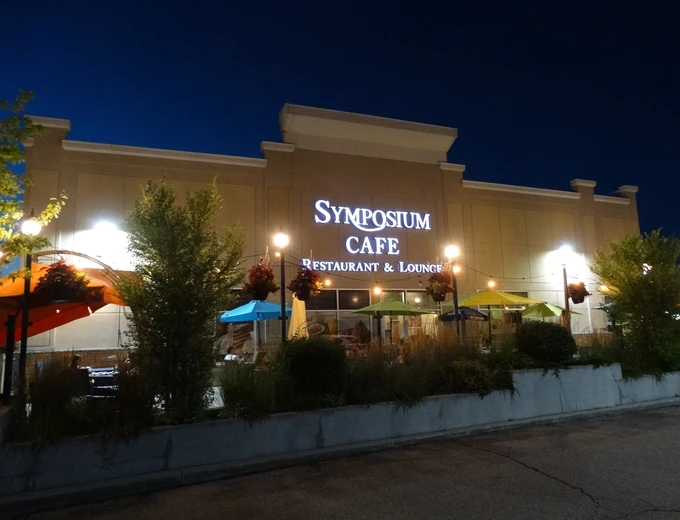 Symposium Cafe Restaurant Aurora family restaurant exterior facade and outdoor patio seating located on Hollandview Trail, beside the Shoppers Drug Mart and down the road from Cineplex Cinemas.